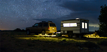 4WD vehicle and towed caravan set up at a campsite at night