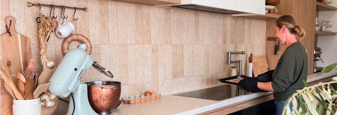 A woman bakes in a kitchen, leaving the oven door open to let heat out