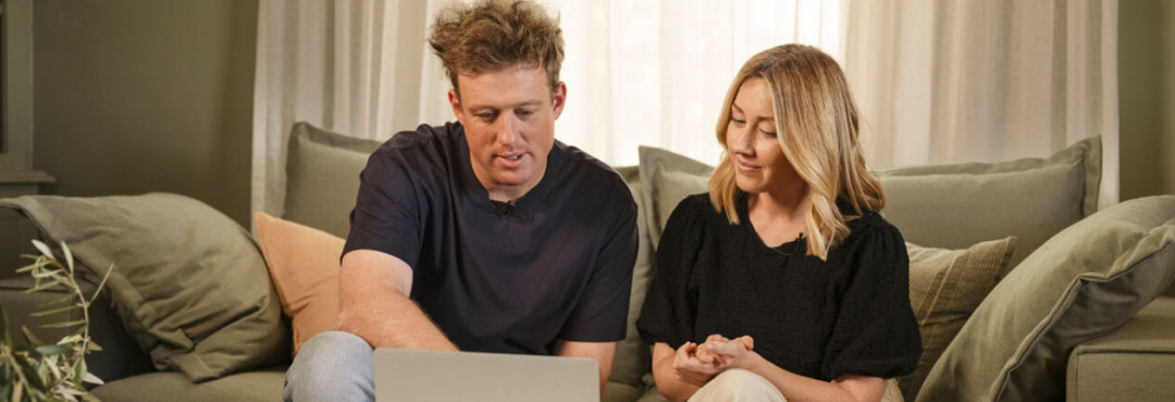 Josh and Jenna visit Green Specs site on a living room sofa looking at a laptop screen