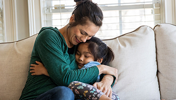 A parent embraces a child on a couch