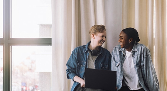 Two colleagues share a friendly moment while looking at a laptop