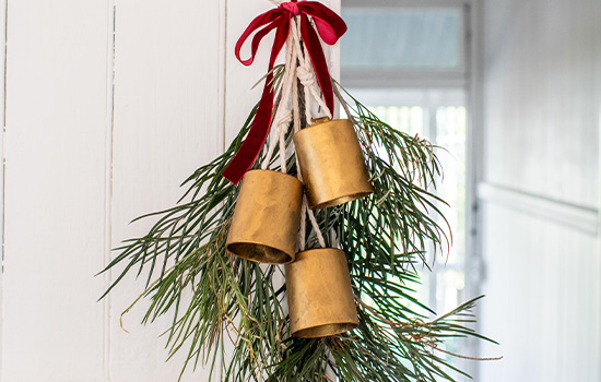 Upcycled golden bells decoration with ribbon and foliage.