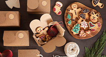 A selection of gingerbread biscuits in Christmas shapes with cardboard boxes.