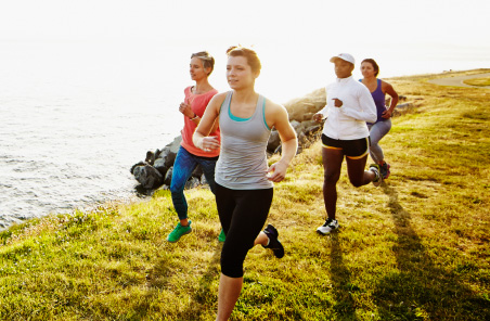 group of people jogging on a cliff top overlooking the ocean