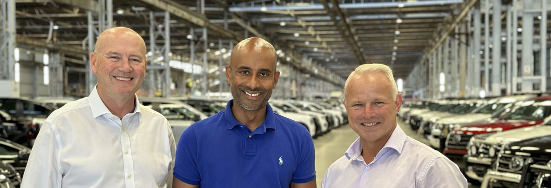 Allianz Australia Managing Director, Richard Feledy stands alongside CJ Jayasinghe, CEO Westside Auto Wholesale and Trevor Bell, WA State Manager Consumer Partners Allianz Australia inside Westside Auto Headquarters with a fleet of motor vehicles parked behind them.