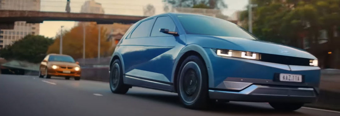 A Hyundai IONIQ 5 EV overtakes a Holden Commodore on a city freeway