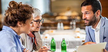 Three people discussing business around a table.