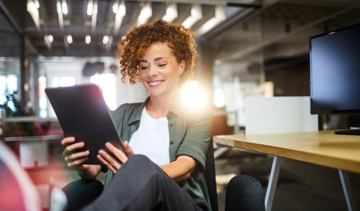 A woman smiling and looking at a tablet