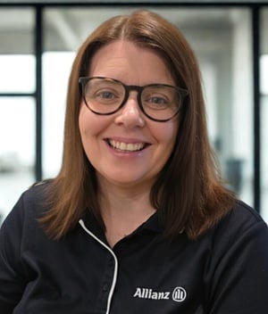 Arna Hickey smiles and wears a navy blue Allianz polo shirt and glasses