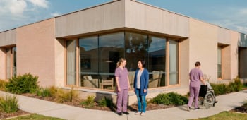 An worker discusses their recovery progress with a colleague at the corner of a health clinic