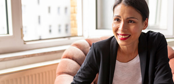 A female healthcare professional sitting in a chair, smiling at the person seated opposite her.