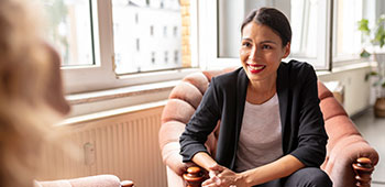 A smiling women sitting on a chair having a conversation.
