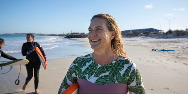 Three ladies walking on the beach with surfboards