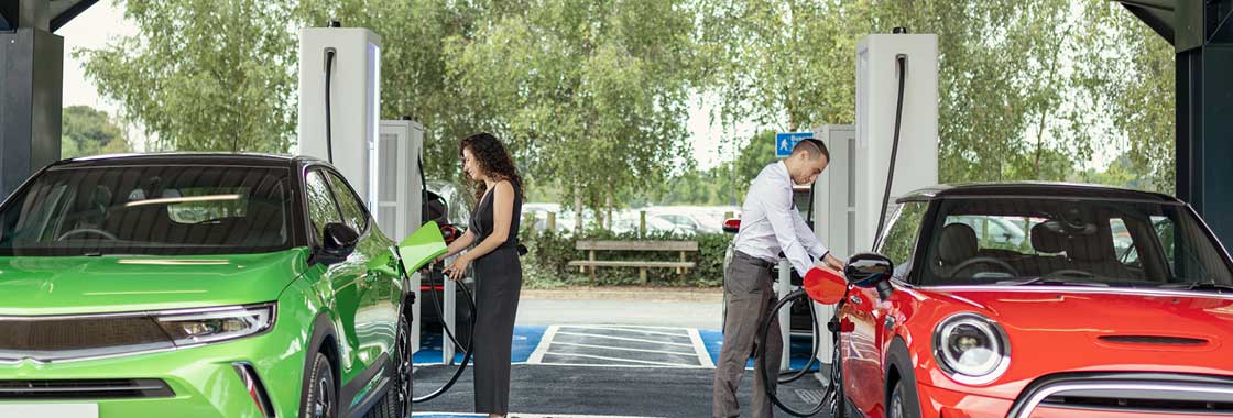 Tow people plugging in their Electric Vehicles at a charging station