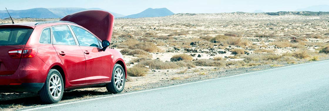 A car with its hood open, parked by the side of the road in a remote area