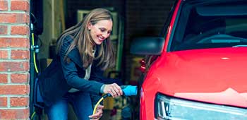 Woman charging electric vehicle at home