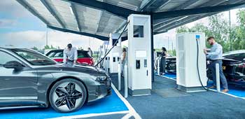 Man charging electric vehicle at charging outlet