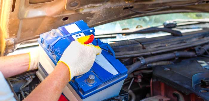 Gloved installer replacing a battery in a vehicle