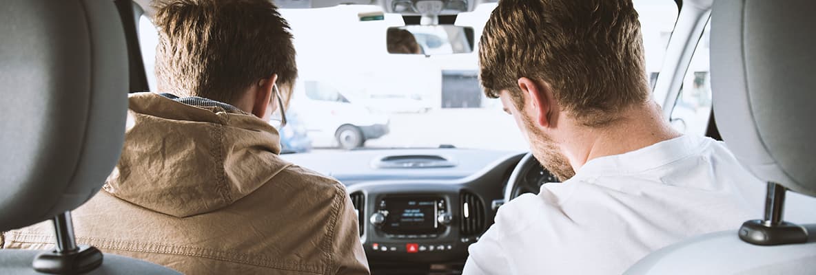 Two men in a car, viewed from the back seat.