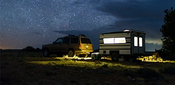 4WD vehicle and towed caravan set up at a campsite at night