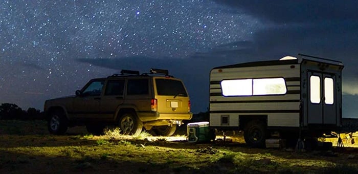 4WD vehicle and towed caravan set up at a campsite at night