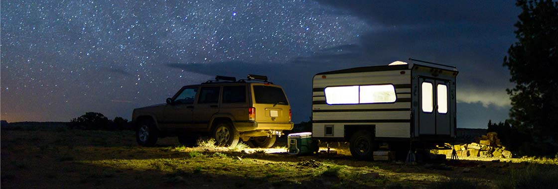 4WD vehicle and towed caravan set up at a campsite at night