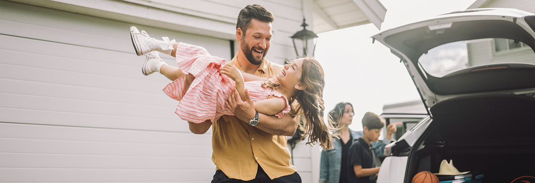 A smiling man carries his laughing daughter.