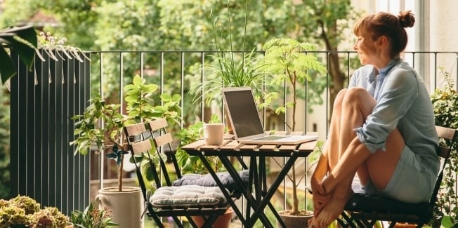 A woman sitting at a table ouside working on her laptop