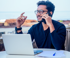 A man talking on a mobile and looking at a laptop screen