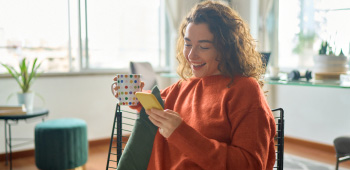 A woman viewing her mobile phone screen while relaxing at home.