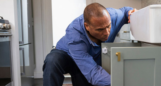 man checking cupboard under the sink