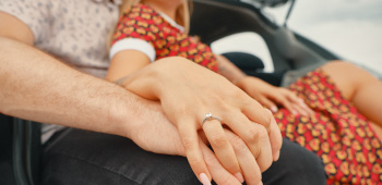 A diamond engagement ring sparkling as a couple hold hands.