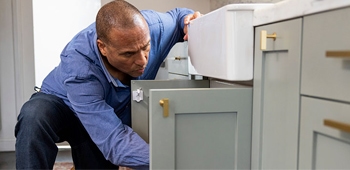 man checking plumbing under a kitchen sink