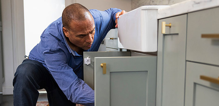 man checking plumbing under a kitchen sink