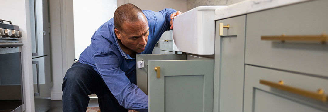 man checking plumbing under a kitchen sink