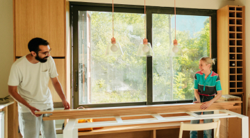 Two people hold a plank of wood during a home renovation