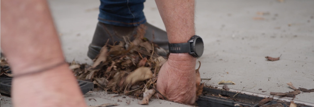 Scotty Cam’s hands clear leaves out of a drain