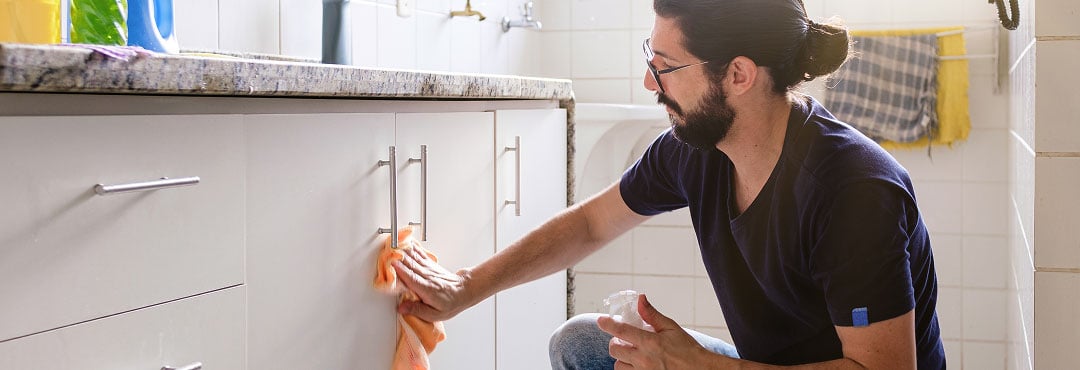 A homeowner cleaning mould from a bathroom cabinet.