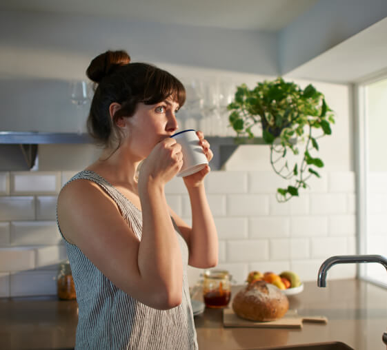 A woman drinking a cup of coffee at home.