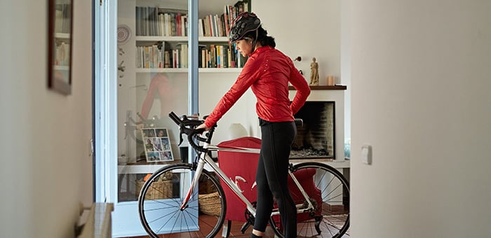 A person in red wheeling their bike outside