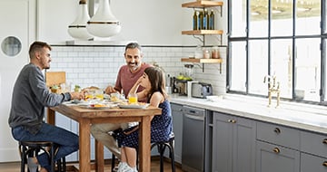 A smiling man carries his laughing daughter
