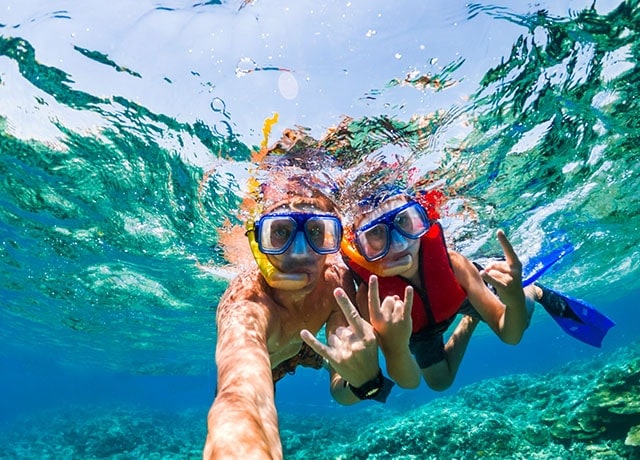 Two kids snorkeling underwater.