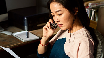 A young woman on the phone looking at a piece of paper