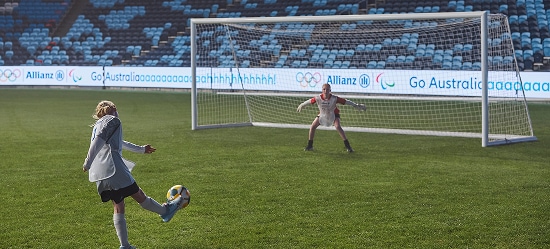 Young girl kicking a soccer ball into a gaol