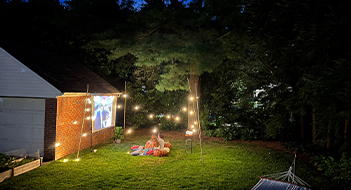 A couple watching a movie on a canvas screen in the garden.