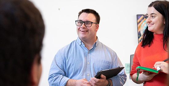 smiling woman and man standing and taking notes