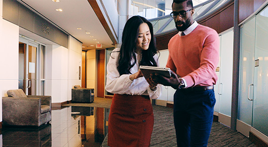 a man and a woman looking at a tablet together in a work environment