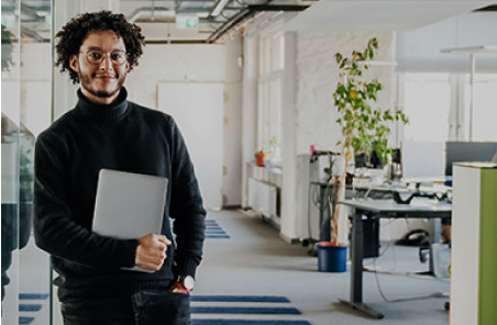 man in an office holding a laptop