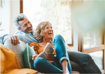A happy couple relaxing on their couch at home.