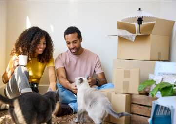 A couple moving into their new home take a break with their cats.